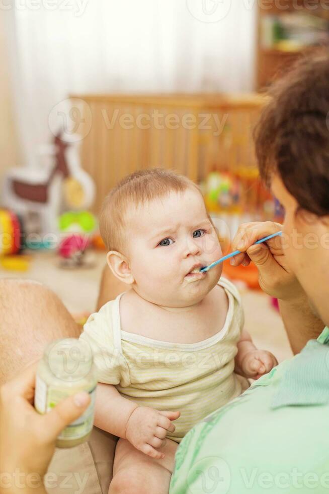 father feeding his cheerful baby photo