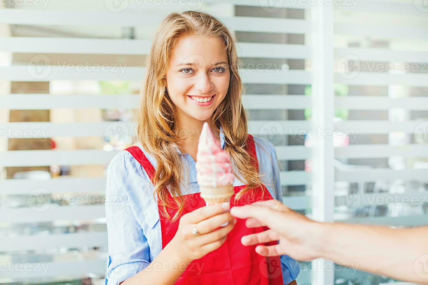 young woman working as ice cream seller giving ice cream to a customer photo