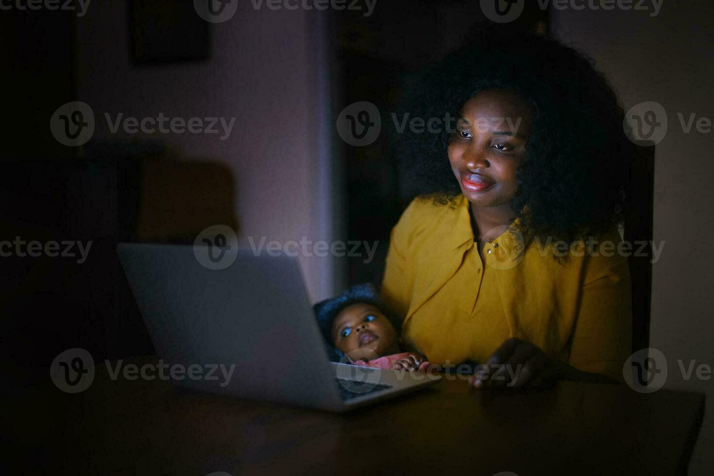 Mother sitting at night with the baby in front of the laptop photo