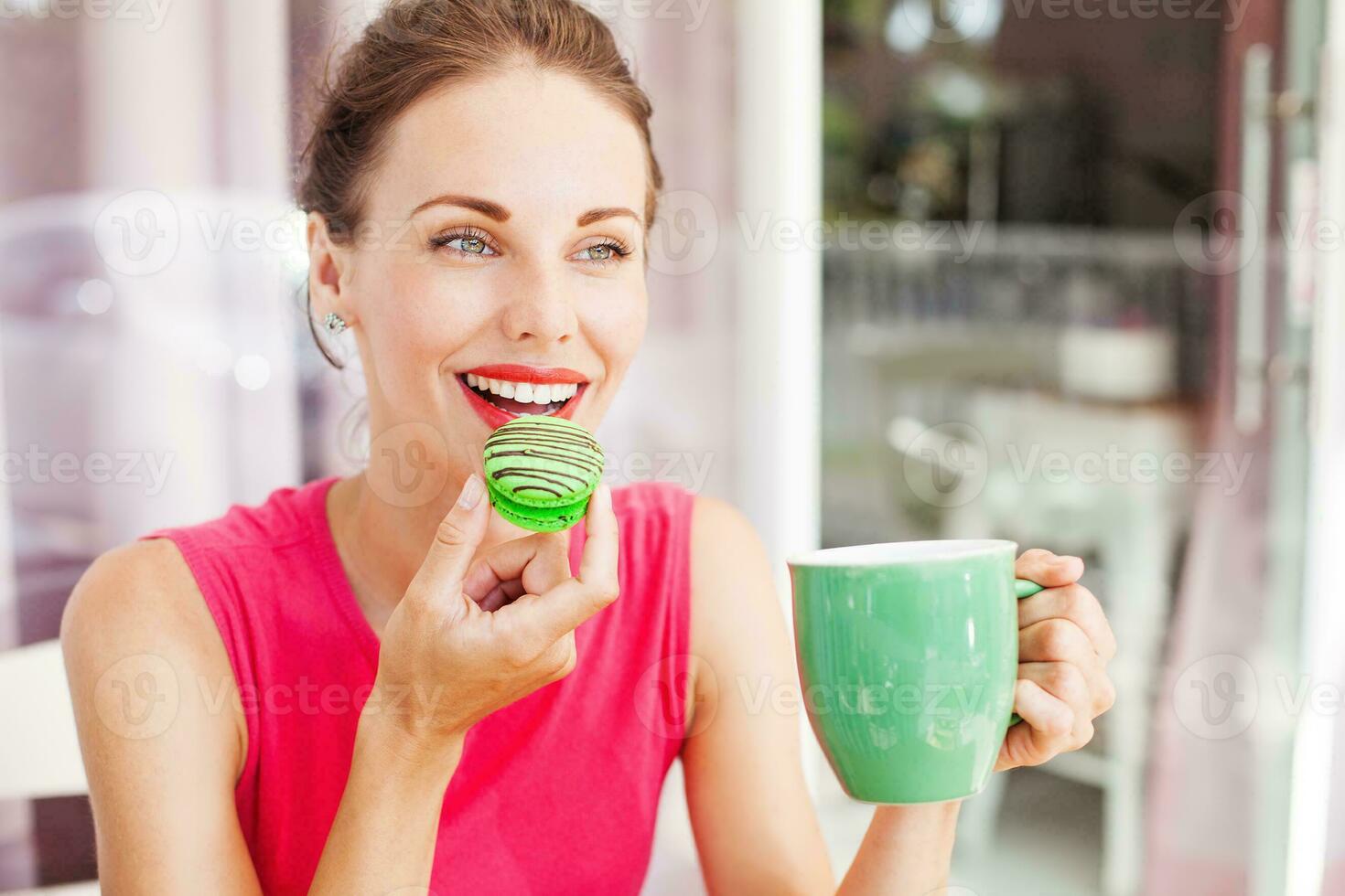 woman looking at macaron she's going to eat. Lovely color combination of pink and green photo