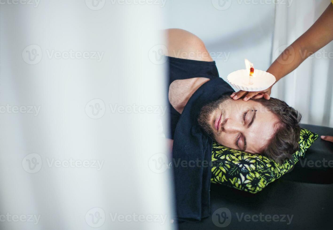 man having an ear candle therapy photo