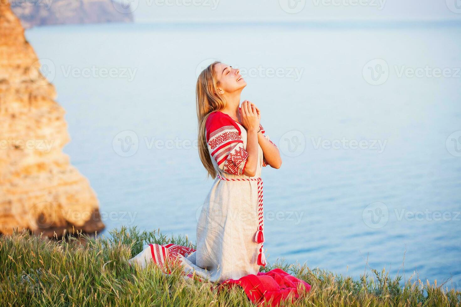 mujer vistiendo tradicional ruso ropa apasionadamente Orando en un mar apuntalar foto