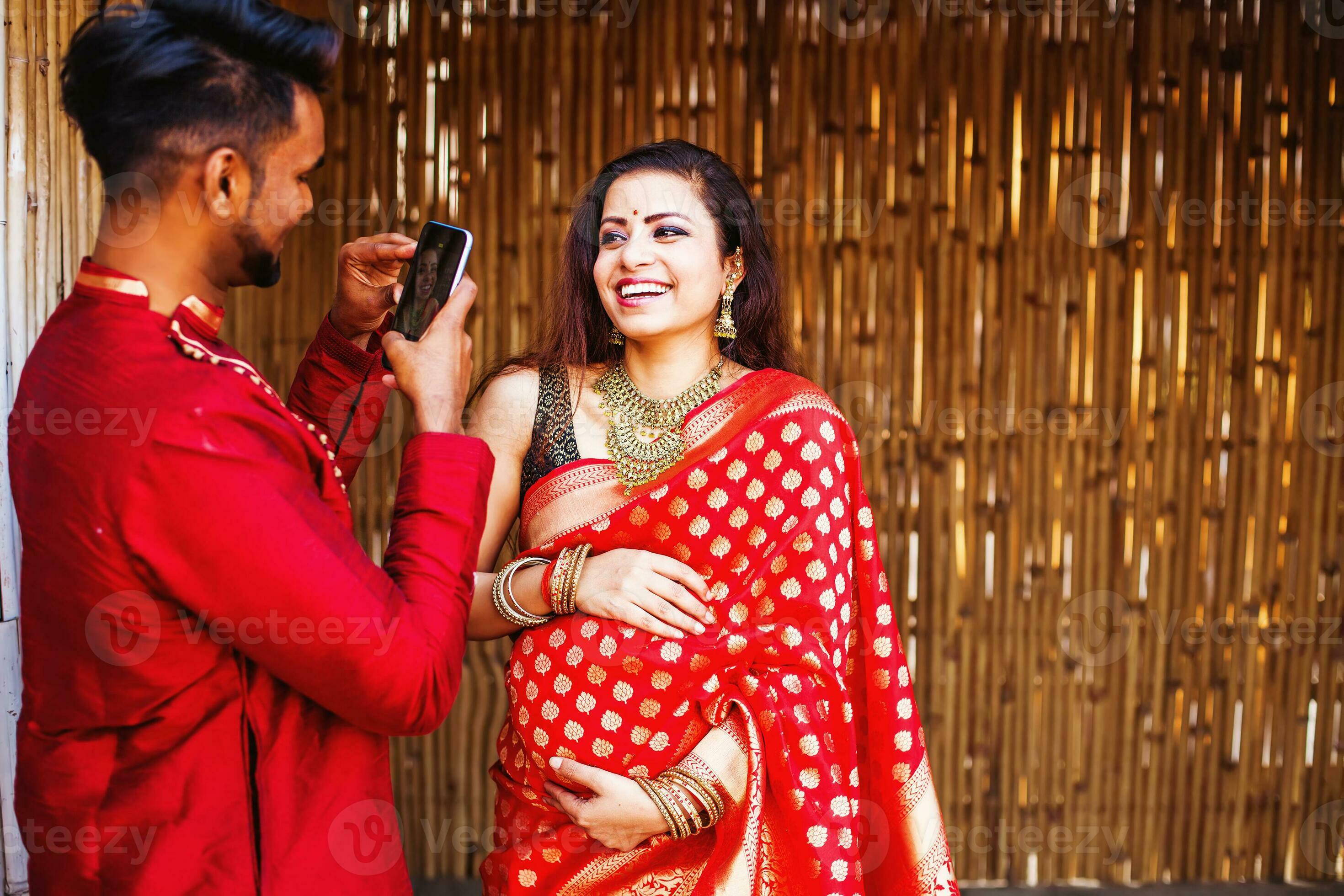 Indian man photographing his pregnant wife wearing saree on mobile phone  camera 24754049 Stock Photo at Vecteezy