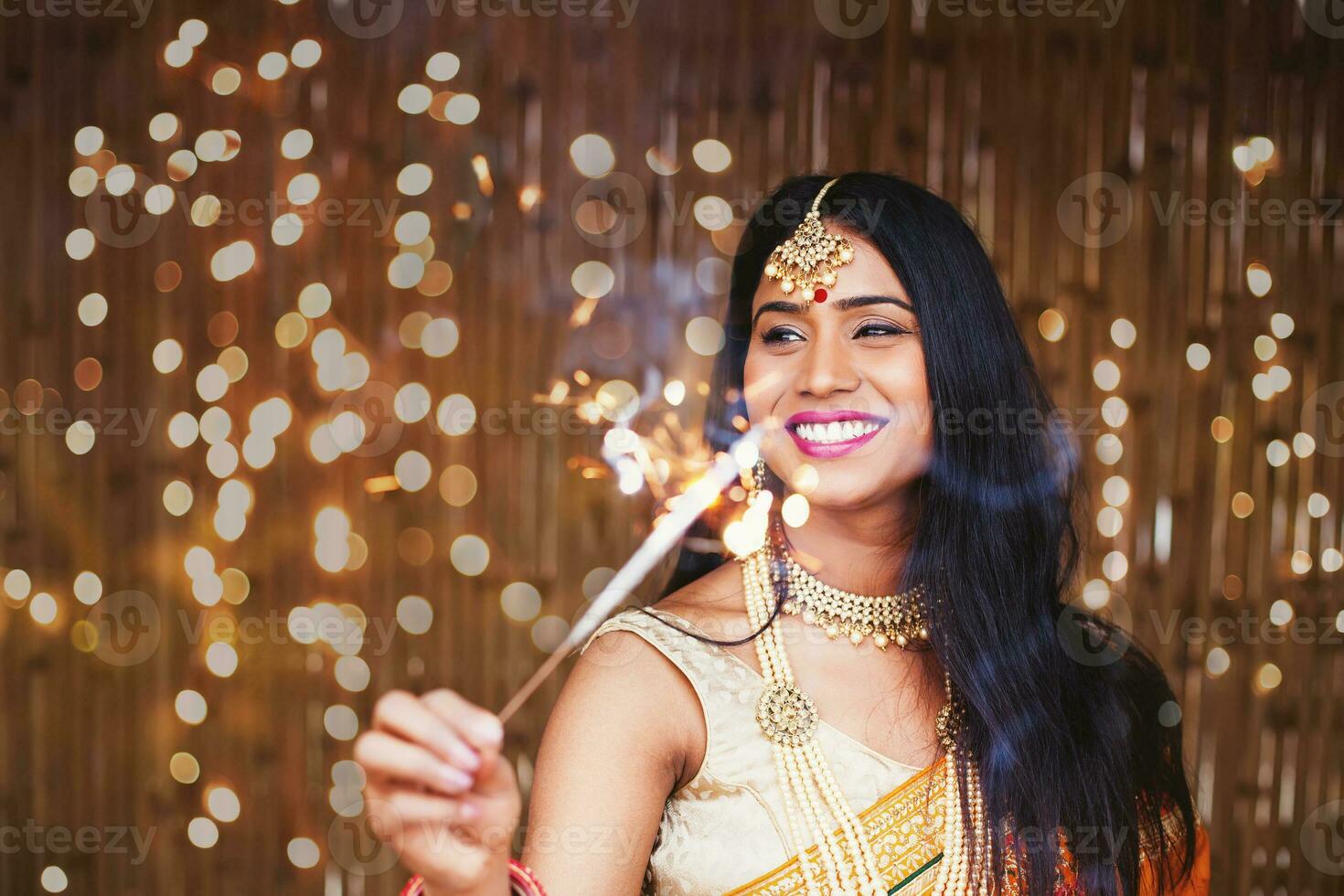 Beautiful Indian woman in traditional clothes holding a sparkler in the evening to celebrate Diwali festival photo