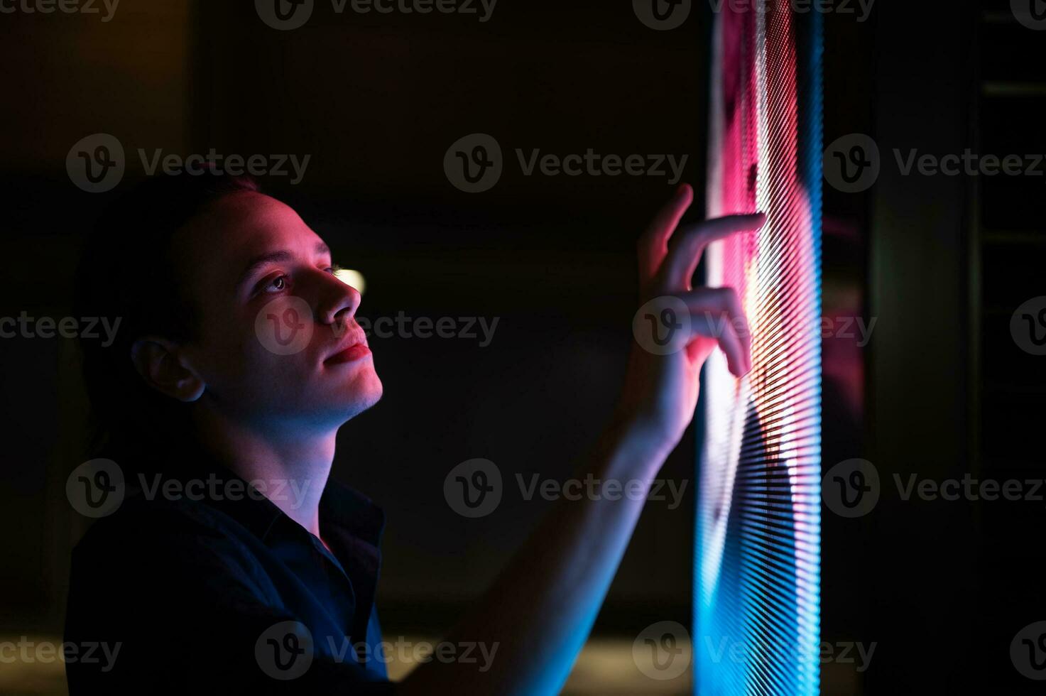 Man clicking on a futuristic screen at night photo