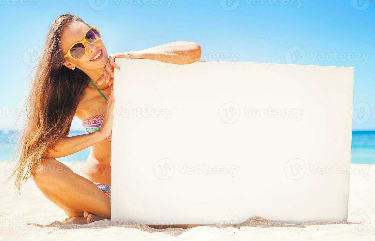 woman on a beach holding a blank board for your text photo