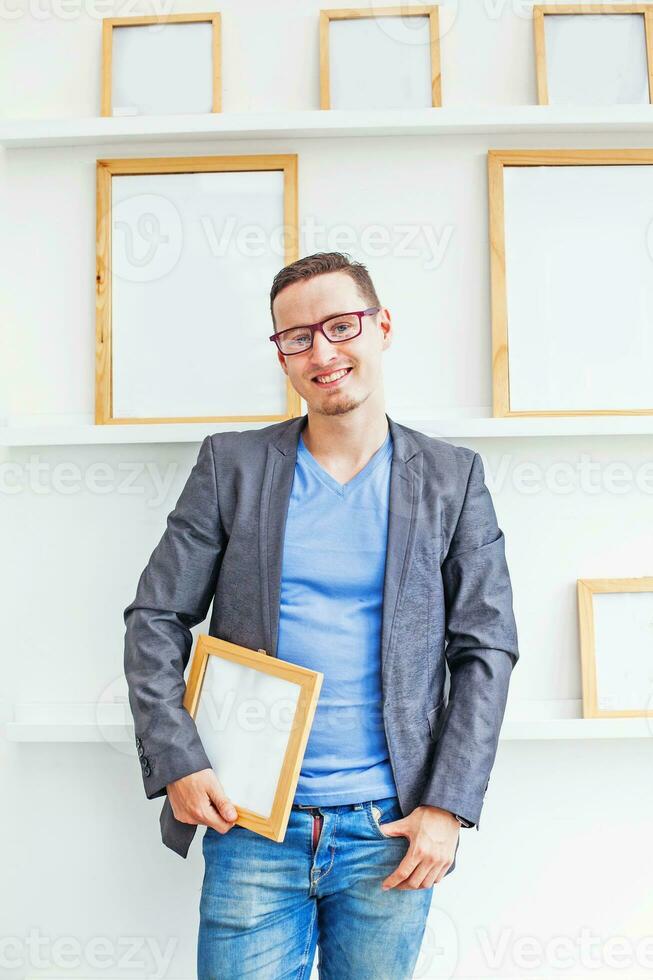 designer holding a blank picture. Many white papers in frames on background photo