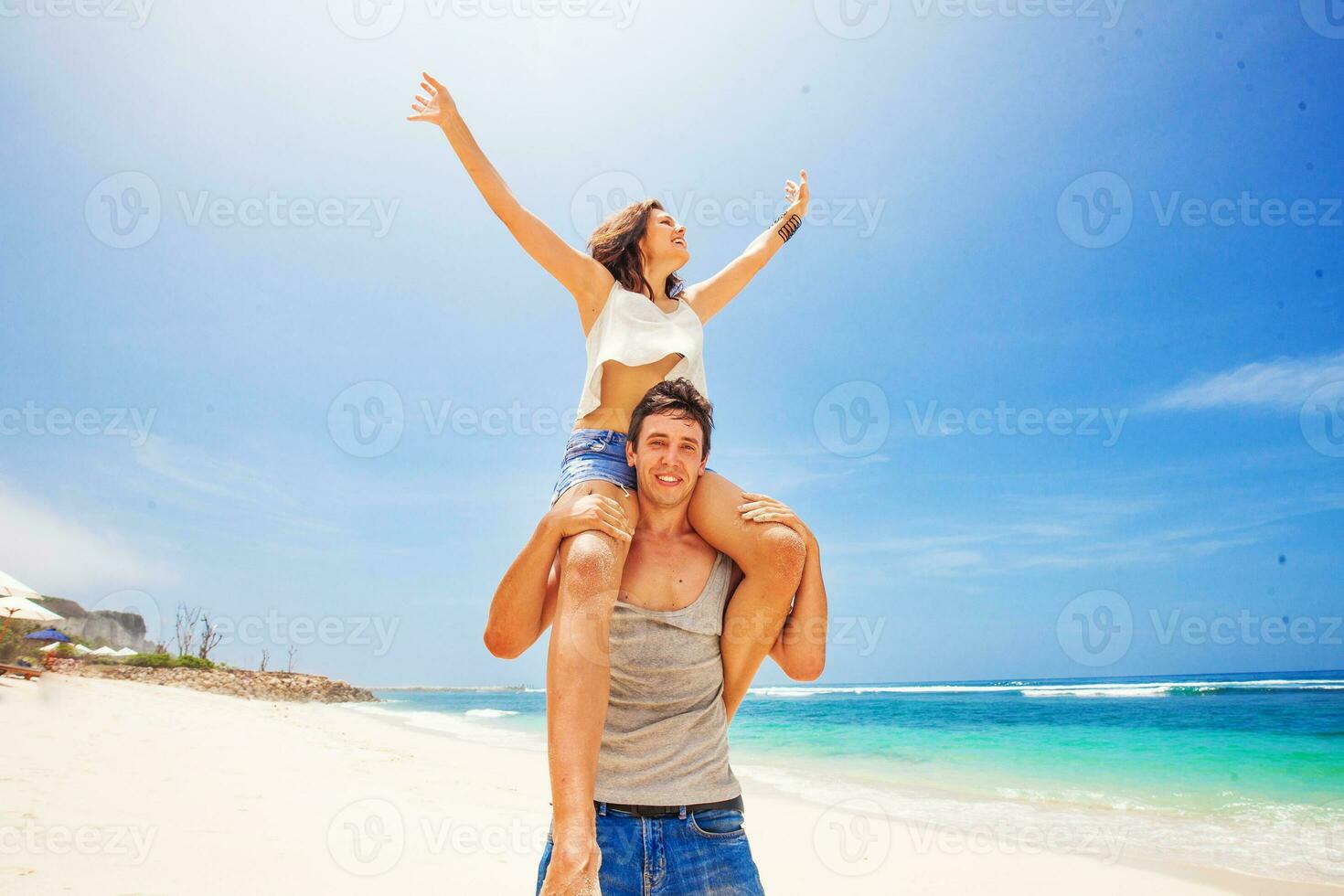 hermosa caucásico Pareja. hombre lleva mujer a cuestas en un playa foto