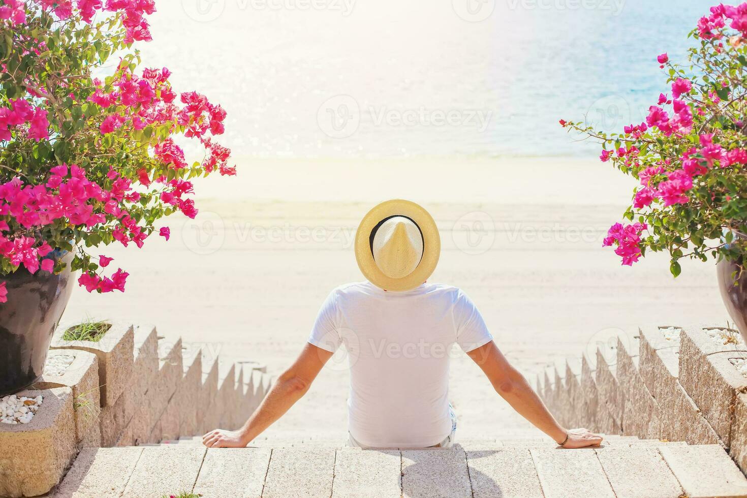 Faceless portrait from the back of a man in a hat sitting on the beach in Dubai photo