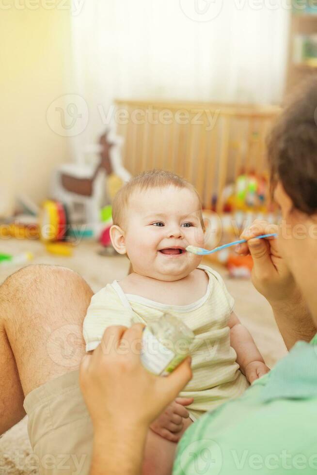 father feeding his cheerful baby photo