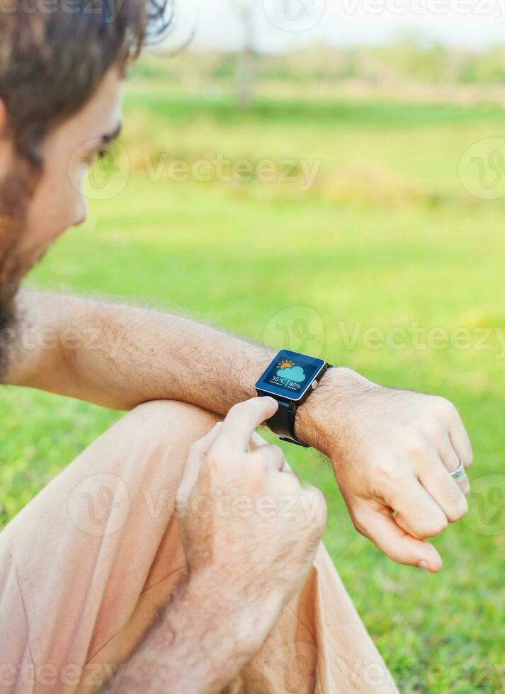 Man clicking on his smart watch showing a weather app photo