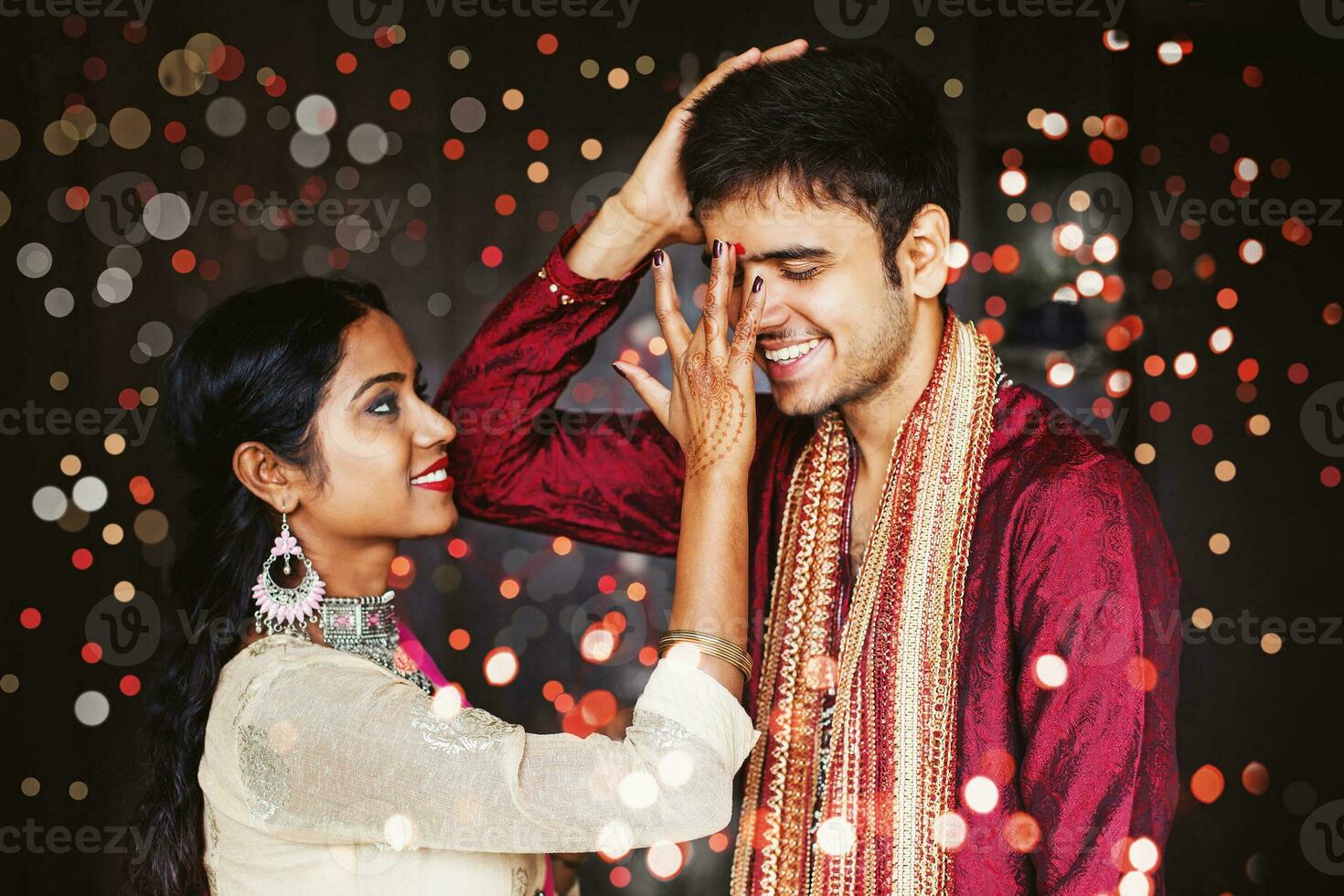 Indian woman is giving blessings to the brother by putting tika on his forehead. Both wearing traditional ethnic clothes. Bokeh on a background photo