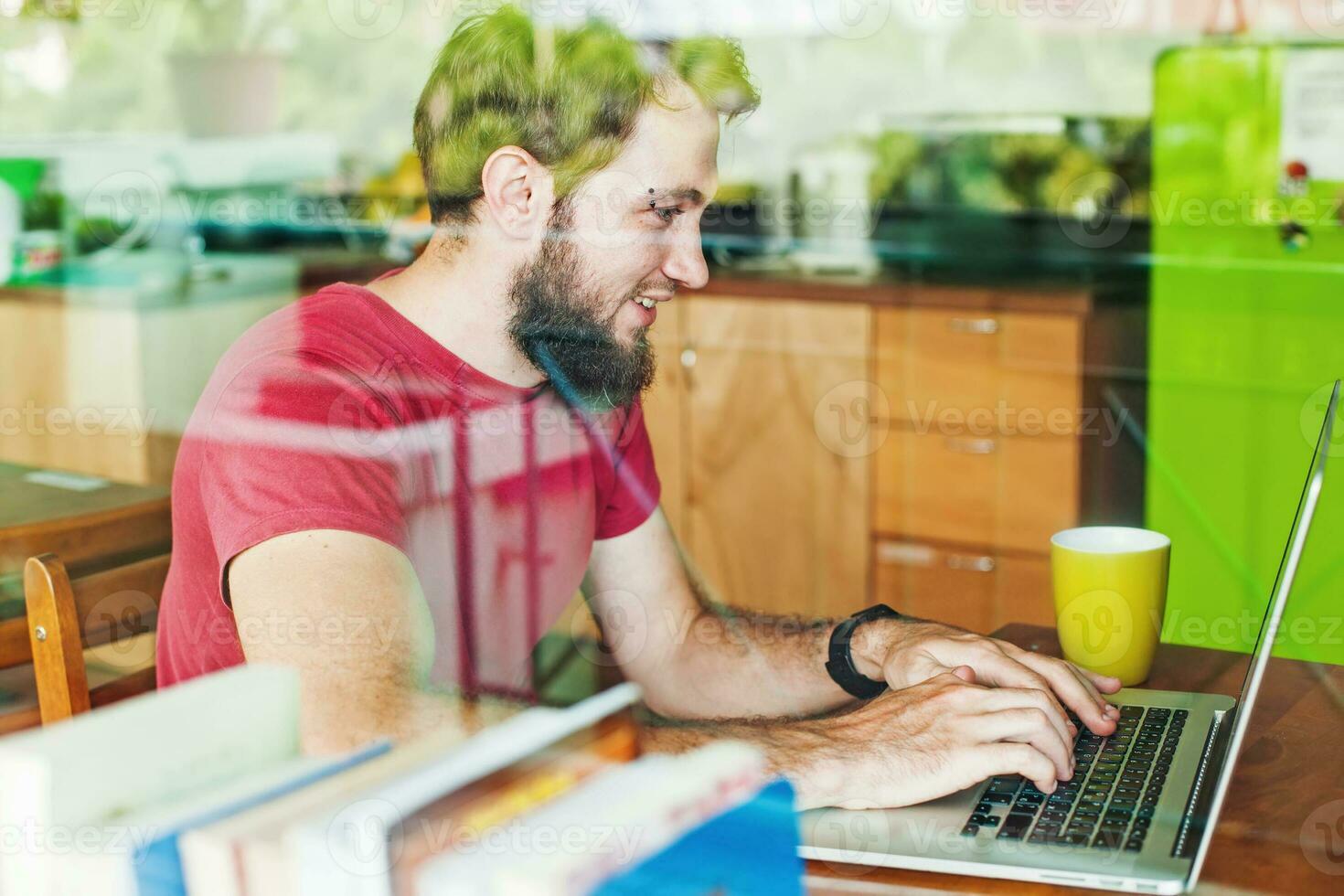 man using his laptop - view through the window photo