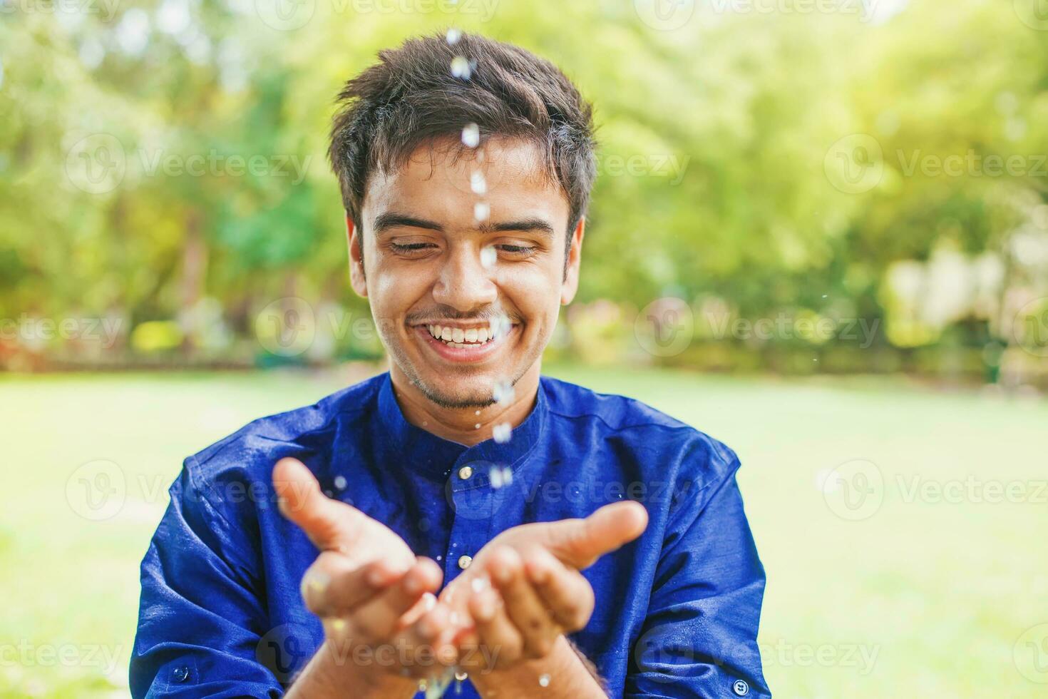 Handsome young indian man splashing drinking water from the spring in nature photo