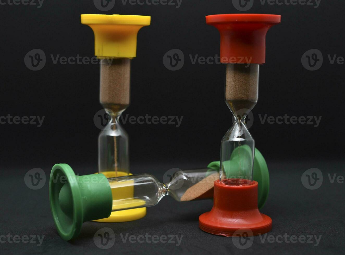 Multicolored glass hourglass on a black background. Vintage hourglass. photo