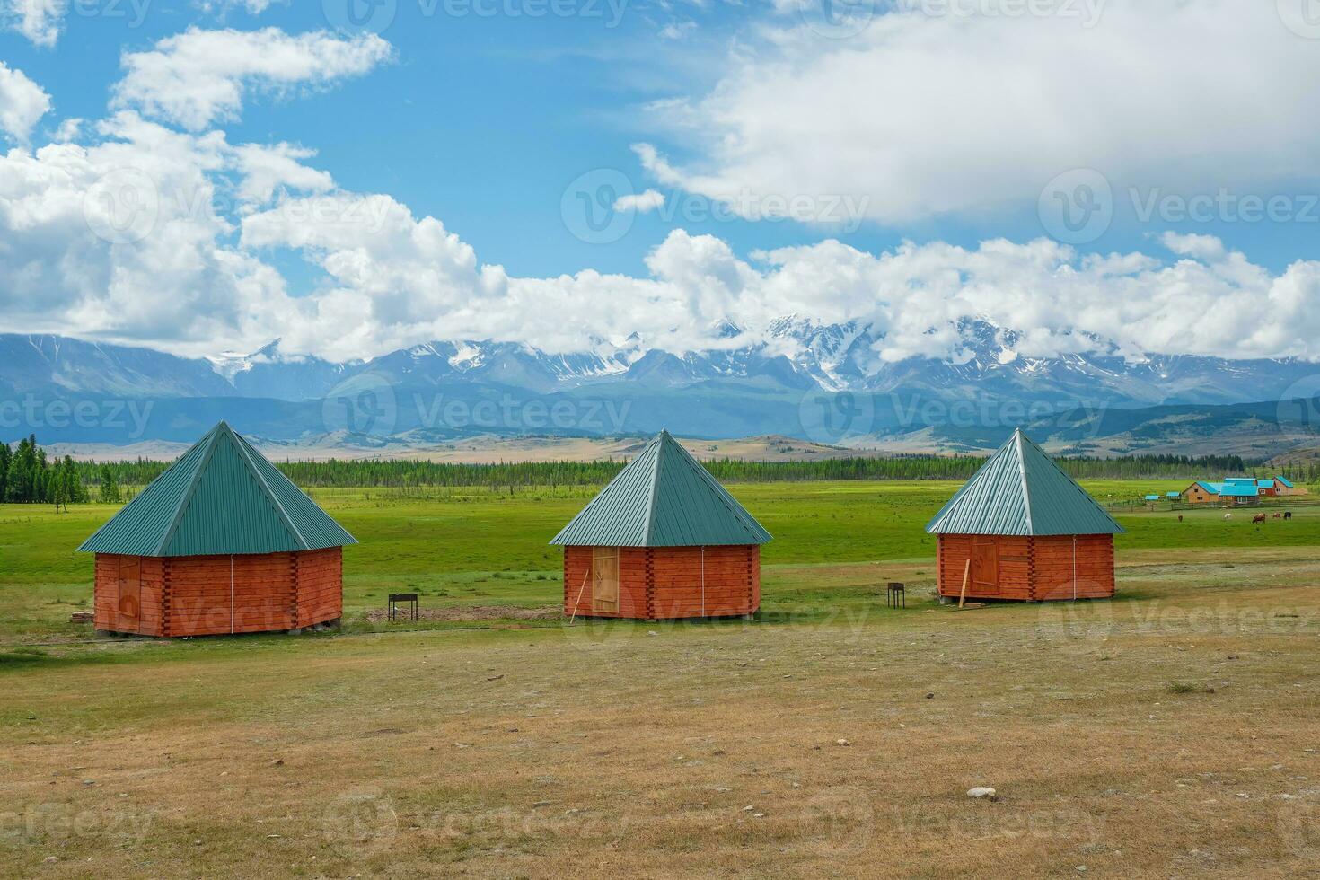 Collective camping, tourist complex, wooden guest houses against the background of green hills. Farmstead in the steppe. Countryside in highlands. Kurai village. Siberia, Altai. photo