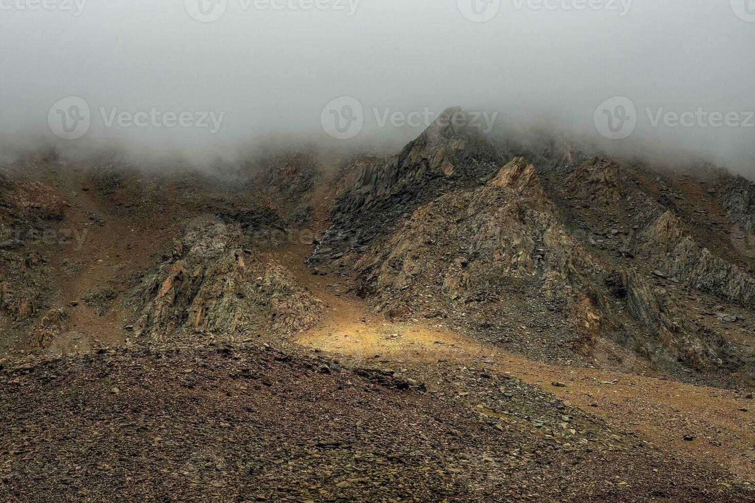 Horror mountain shadows. Dramatic fog among giant rocky mountains. Ghostly atmospheric view to big cliff. Low clouds and beautiful rockies. Minimalist scenery mysterious place. photo