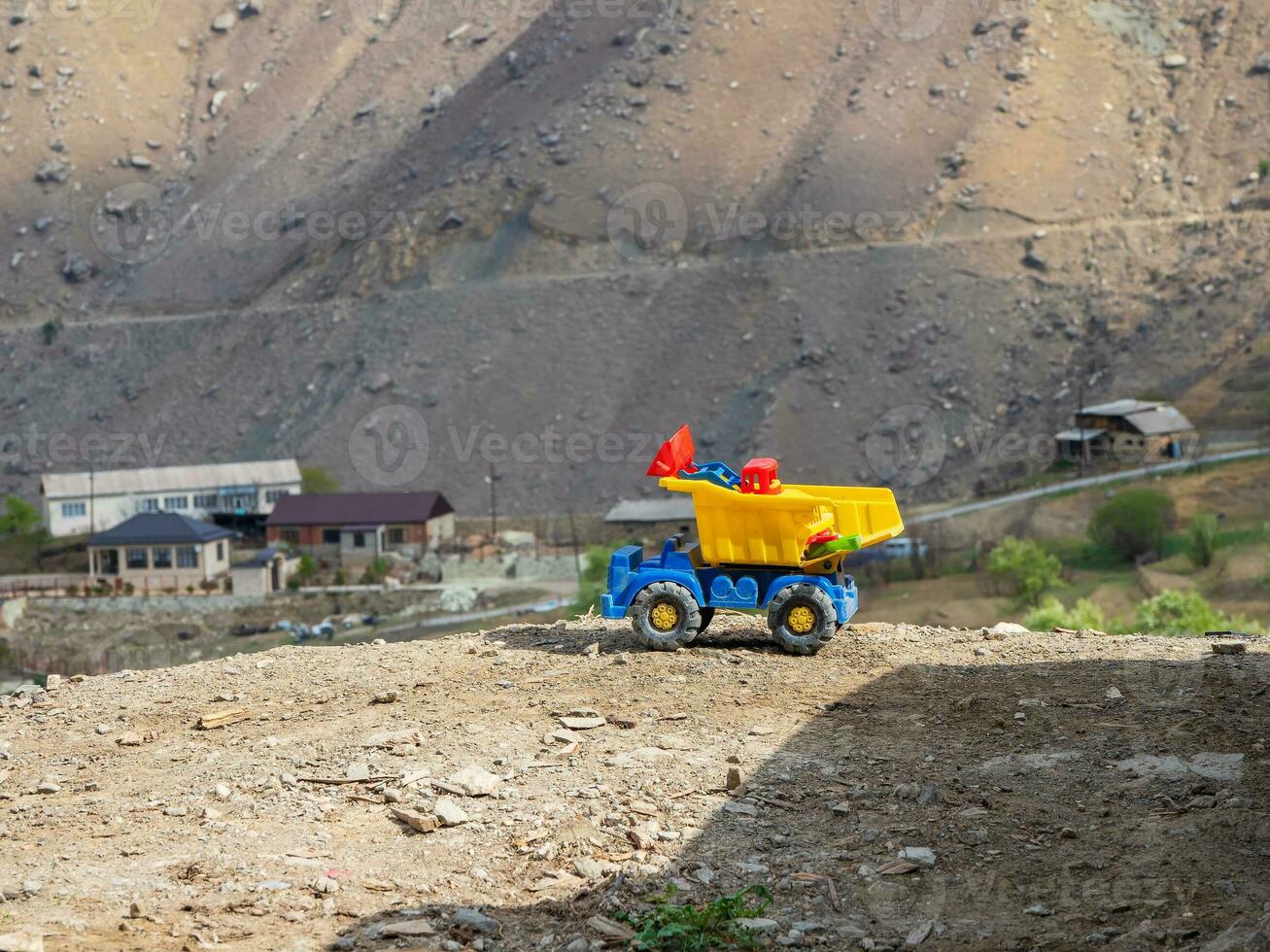 Yellow toy dump truck. Ore mining, work in the mountains concept. photo