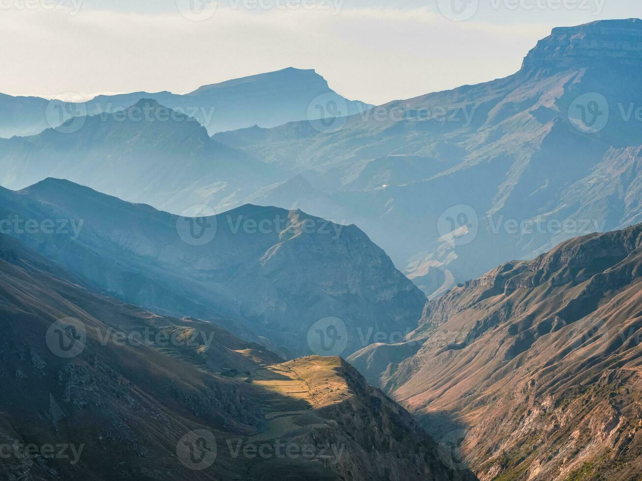 Soft focus. Scenic dawn mountain landscape with light fog in valley among mountains silhouettes under cloudy sky. Vivid sunset or sunrise scenery with low clouds in mountain valley in soft color. photo