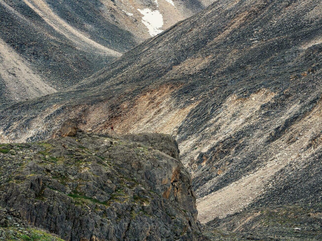 Small figure of a tourist with a backpack on a stone mountain sl photo