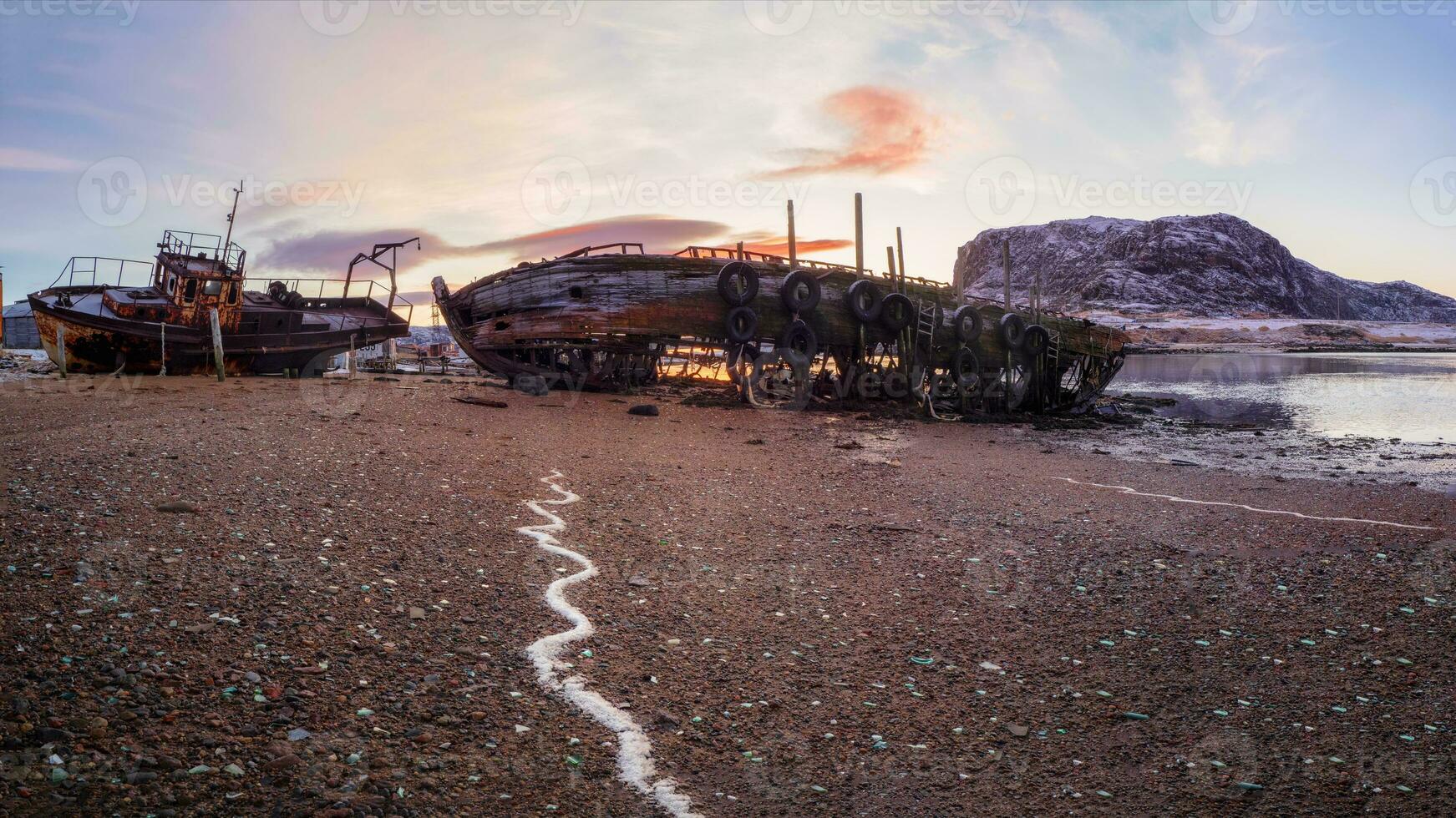 An old rusty fishing boat abandoned by a storm on the shore. Graveyard of ships, old fishing village on the shore of the Barents sea, the Kola Peninsula, Teriberka photo