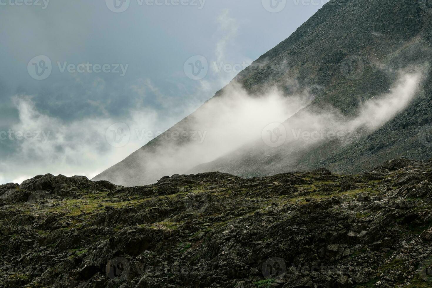Low clouds, changeable weather in the mountains. Scenic alpine landscape with gray low clouds and sunlight. photo