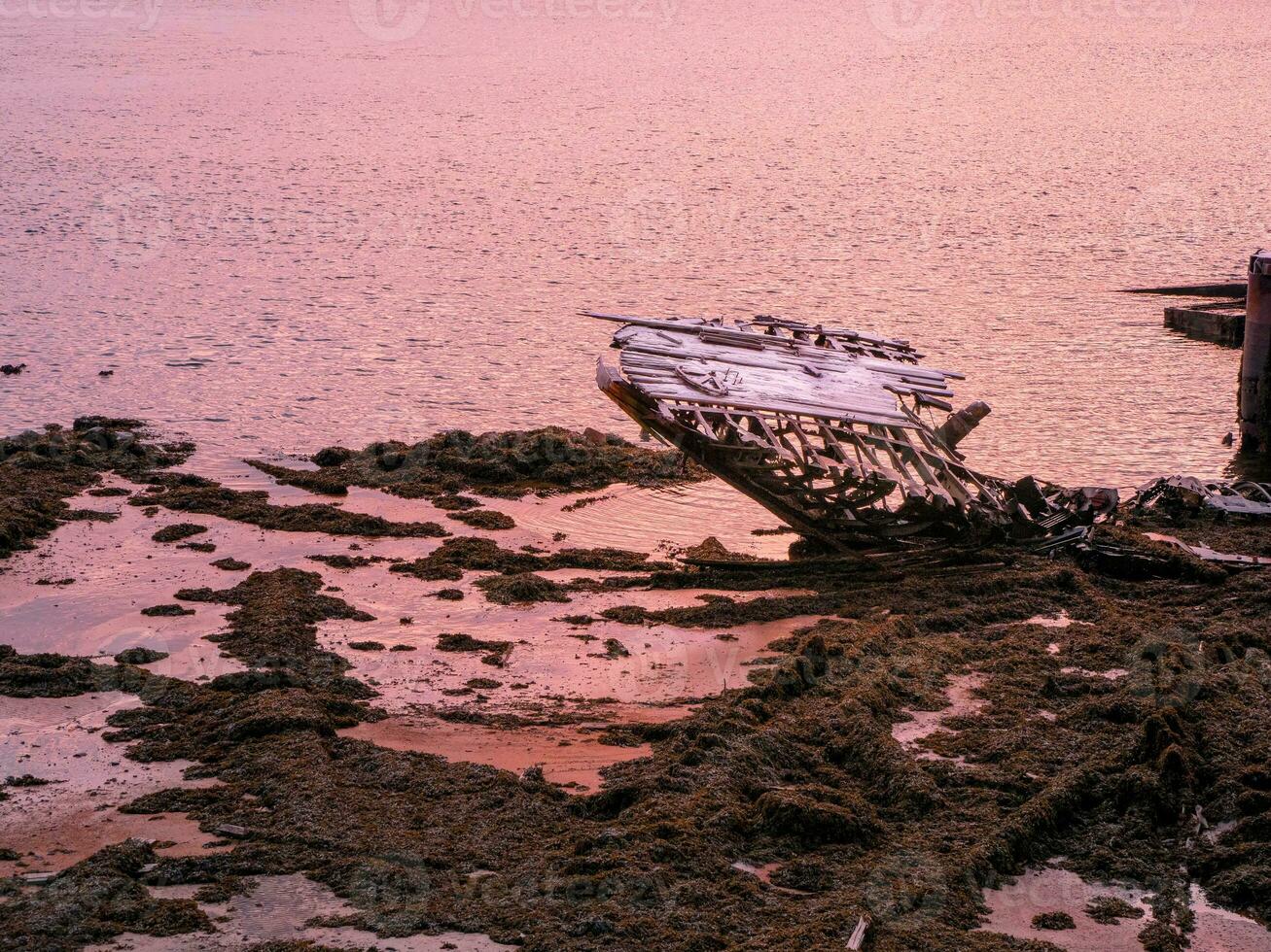 An old rusty fishing boat abandoned by a storm on the shore. Graveyard of ships. photo
