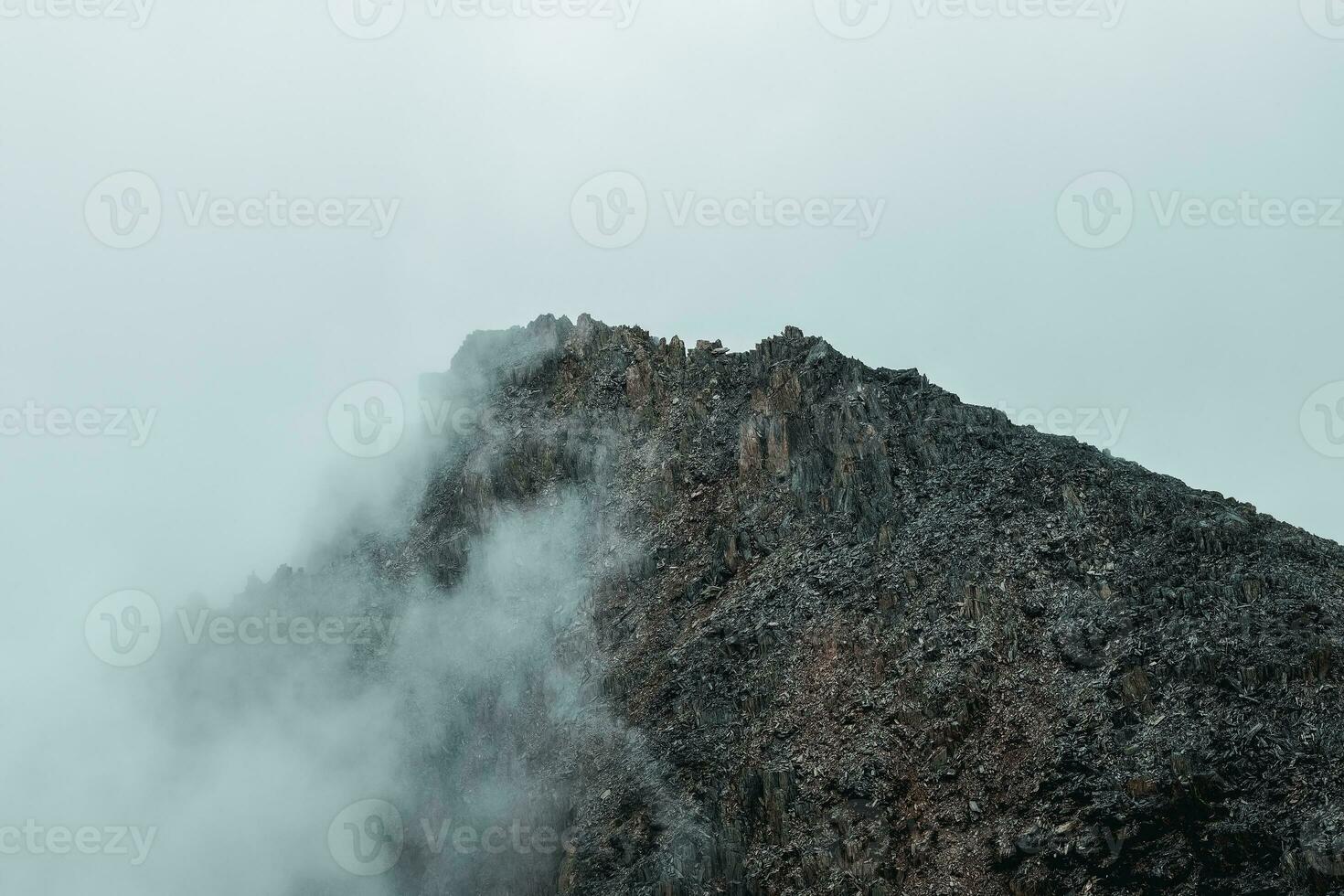 Horror mountain shadows. Dramatic fog among giant rocky mountains. Ghostly atmospheric view to big cliff. Low clouds and beautiful rockies. Minimalist scenery mysterious place. photo