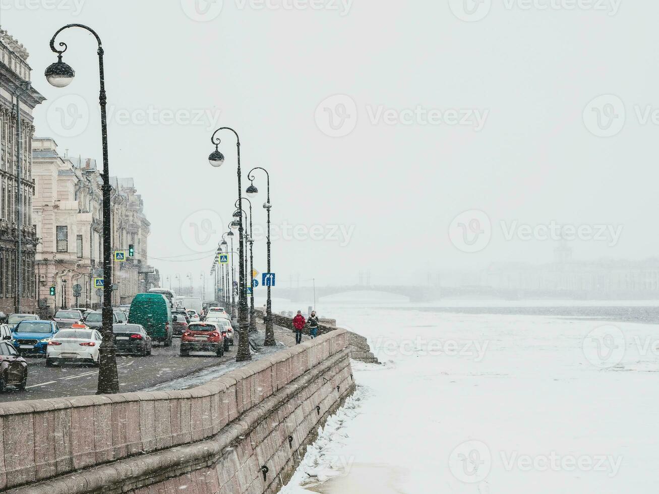 Spring snowfall in St. Petersburg. Traffic jam on the Neva River embankment. photo