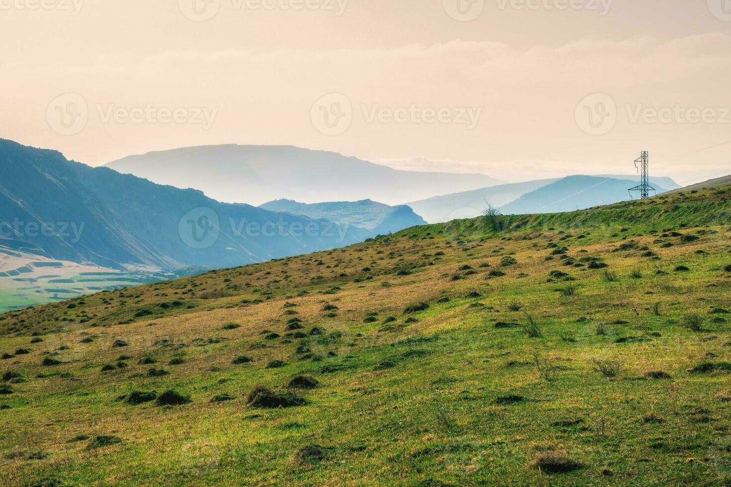 Network of wires and telegraph poles on the mountain hills. Atmospheric landscape with silhouettes of mountains on background of pink dawn sky. Sundown in faded tones. photo