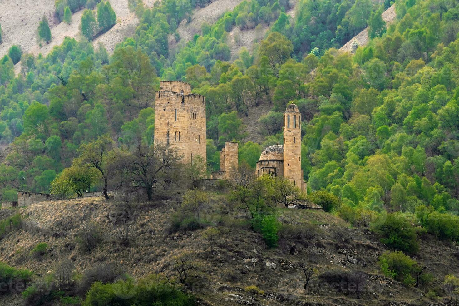 Stone ancient monastery on the green mountain. Memorial complex Vatan, Gunib district in Dagestan. Russia. photo