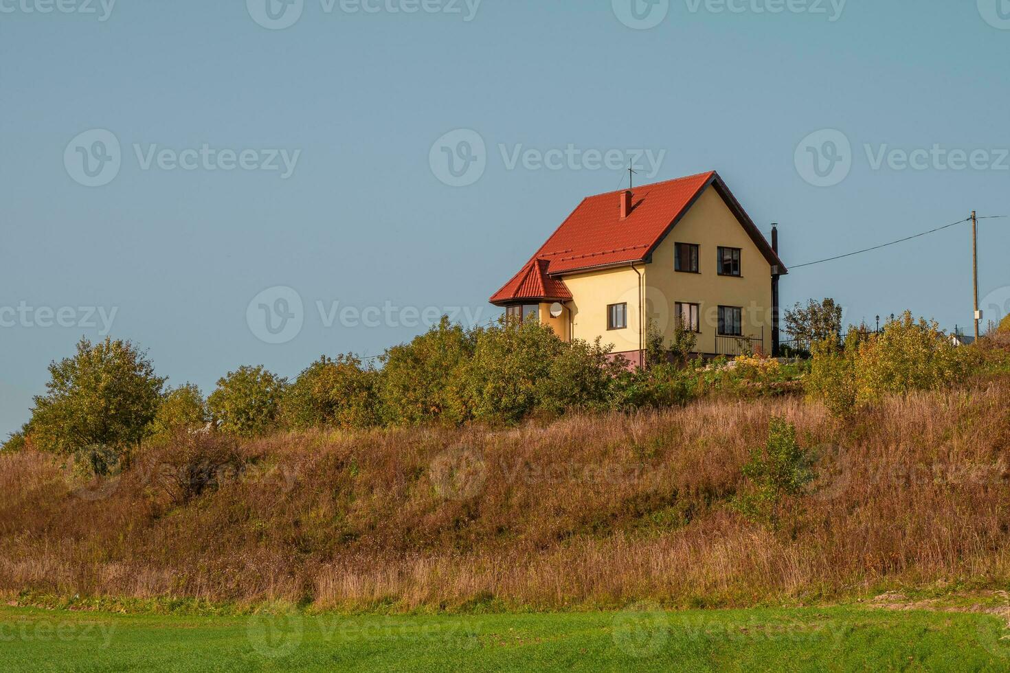 un moderno amarillo cabaña con un rojo techo en un verde colina. foto