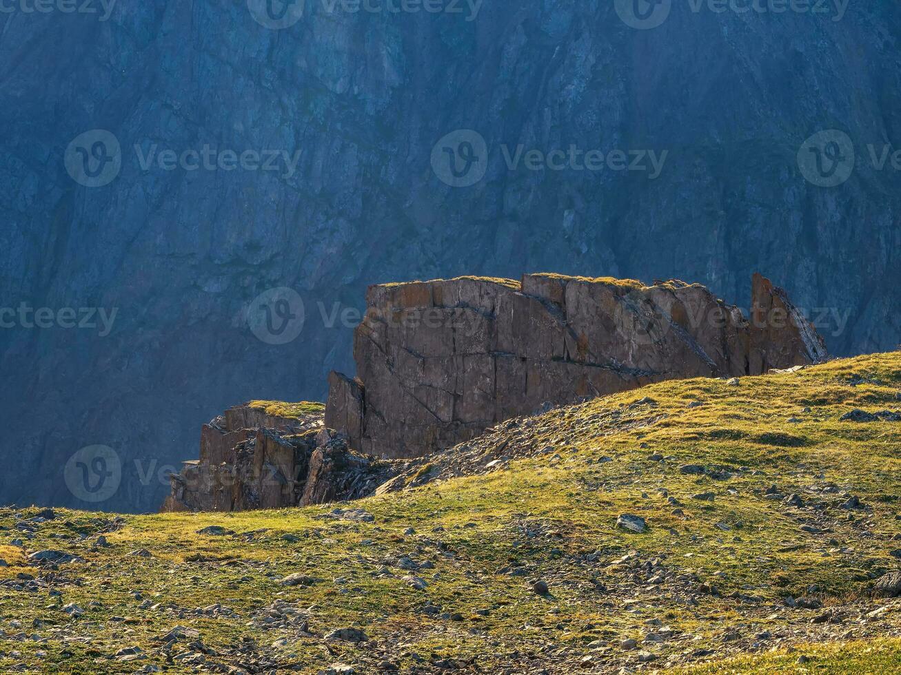 Large rocky ledge above the cliff. Dangerous mountain couloir. Colorful sunny landscape with cliff and big rocky mountains and epic deep gorge. High stone peaks of Altai mountains. photo