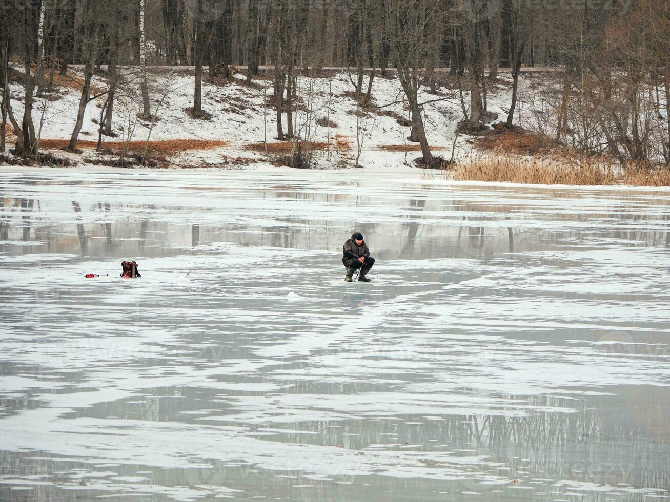 Dangerous fishing on wet spring ice. Fisherman on wet melting ice. photo