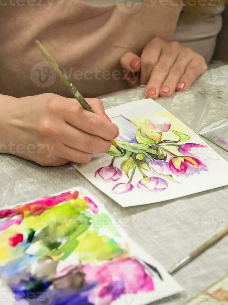 Brush in the hands of the artist, watercolor painting, creativity with many colors. Vertical view. photo