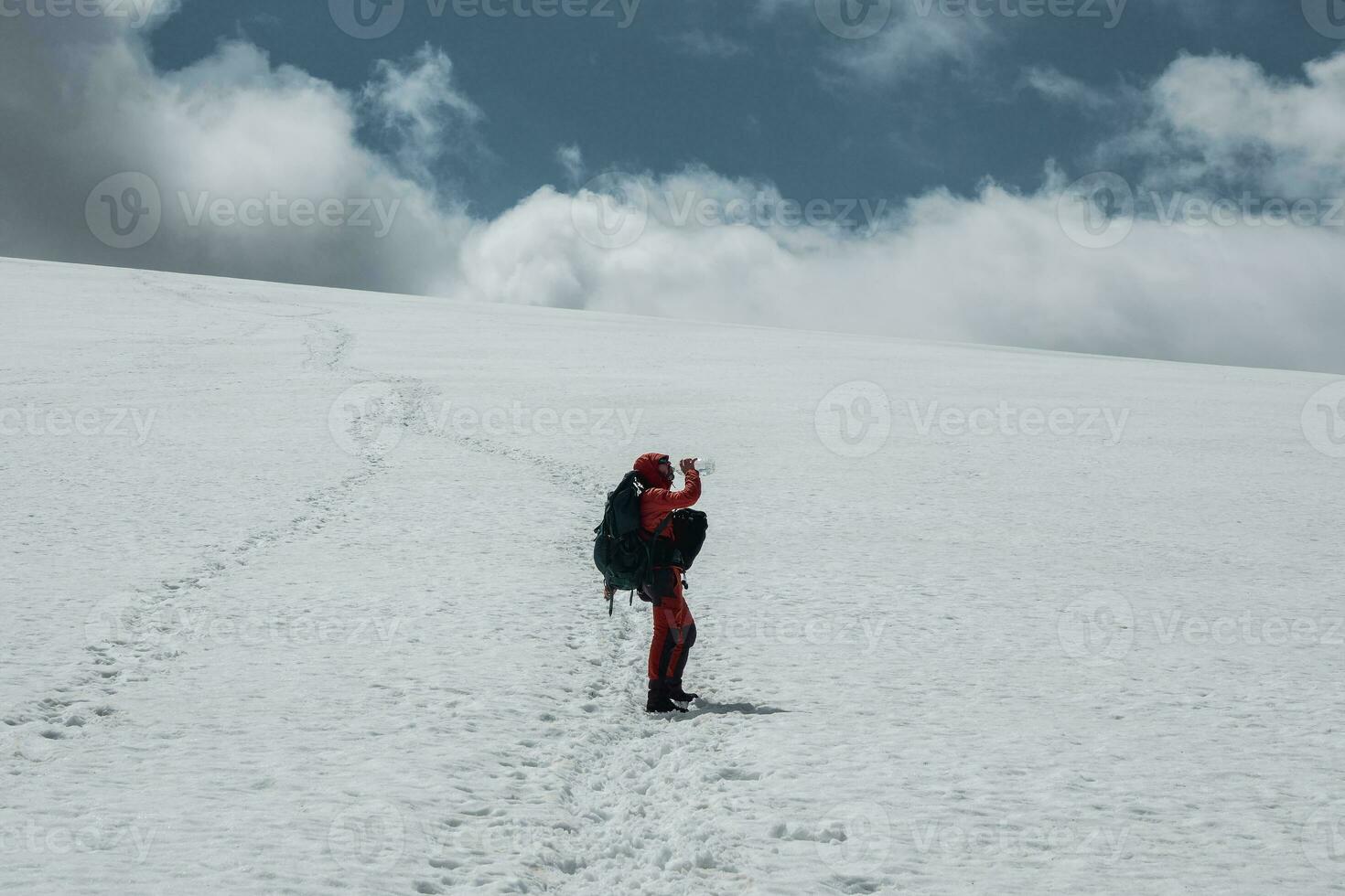 Male climber drinks water on a snowy mountainside while climbing. photo