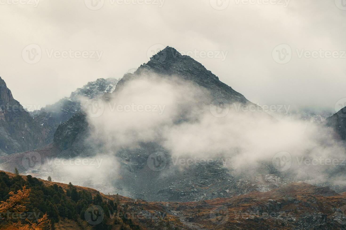 Morning mountain background. Dramatic fog among giant rocky mountains. Ghostly atmospheric view to big cliff. Low clouds and beautiful rockies. Minimalist scenery mysterious place. photo