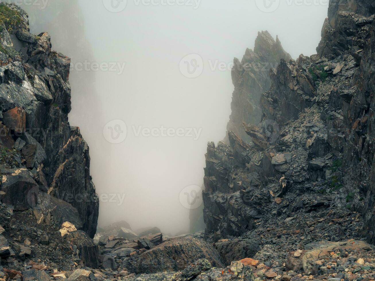 Horror mountain shadows. Dramatic fog among giant rocky mountains. Ghostly atmospheric view to big cliff. Low clouds and beautiful rockies. Minimalist scenery mysterious place. photo