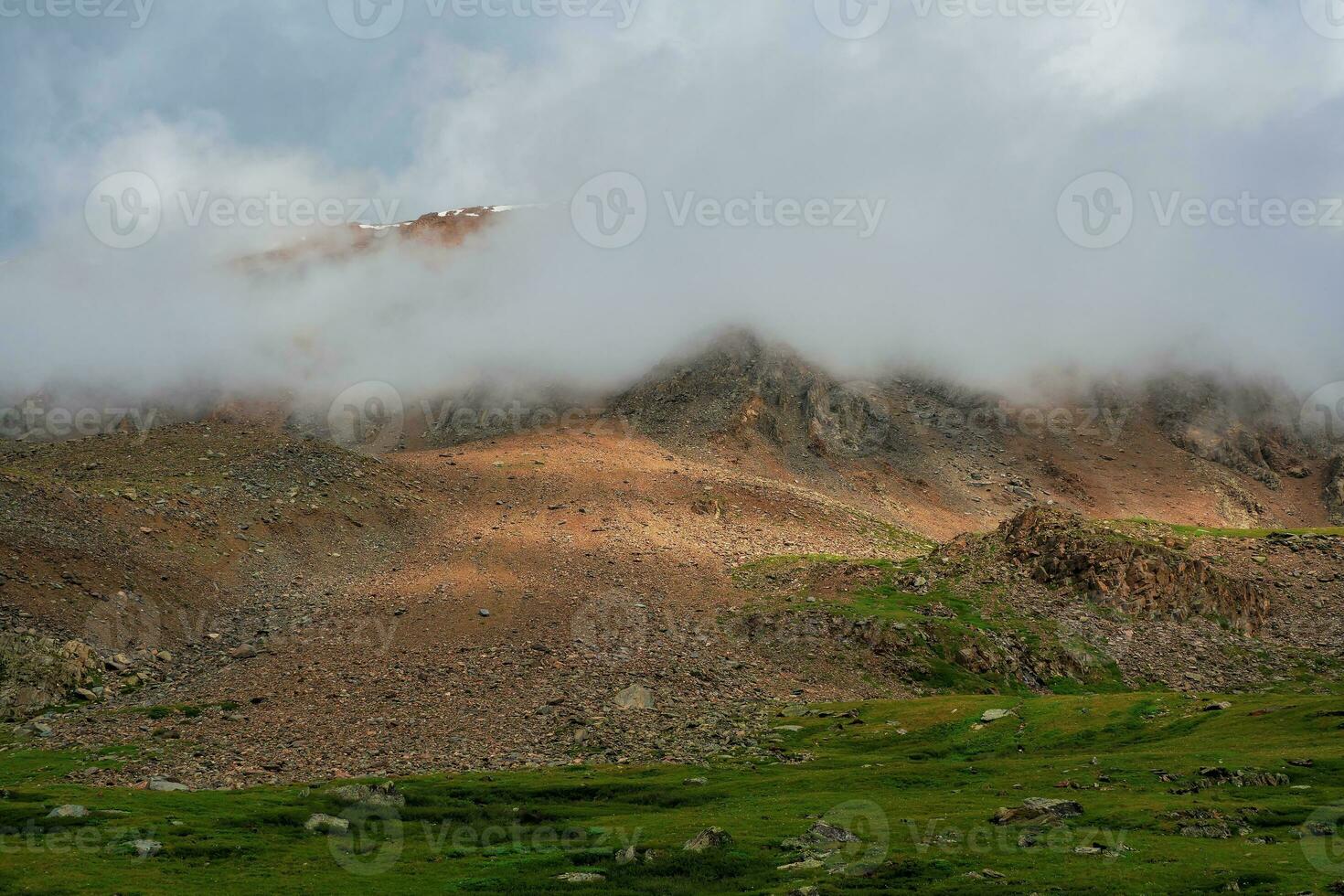 Dramatic fog among giant rocky mountains. Ghostly atmospheric view to big cliff. Low clouds and beautiful rockies. Minimalist scenery mysterious place. photo
