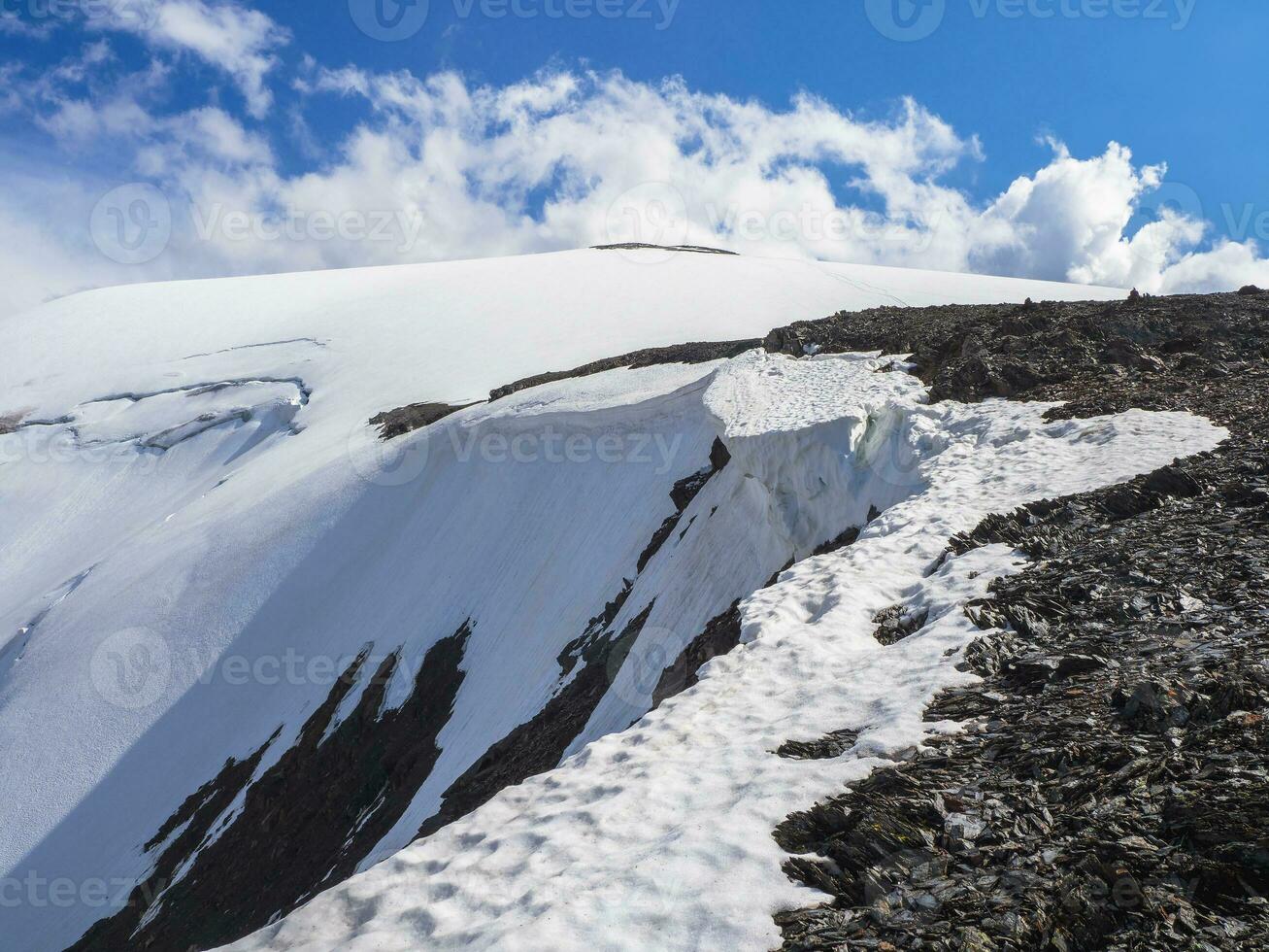 Dangerous snow ledge on the top of the mountain. Ledges from the snowy mountains. Cliffs and large rocks. Dangerous terrain. photo