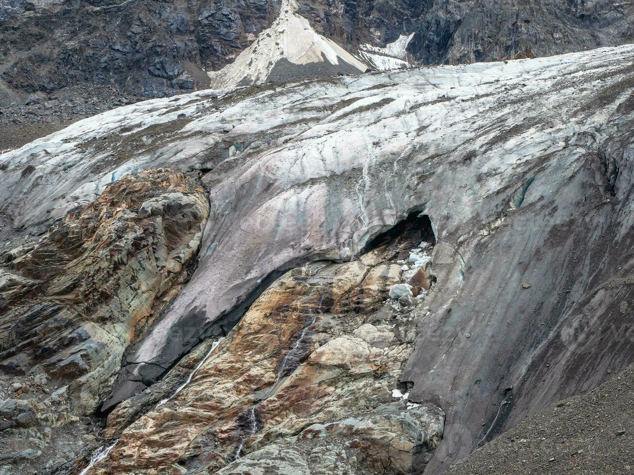 Melting glacier texture. Minimalist nature background of glacier surface with big cave and cracks. Minimal natural backdrop of icy wall and blocks of ice from glacier close up. photo