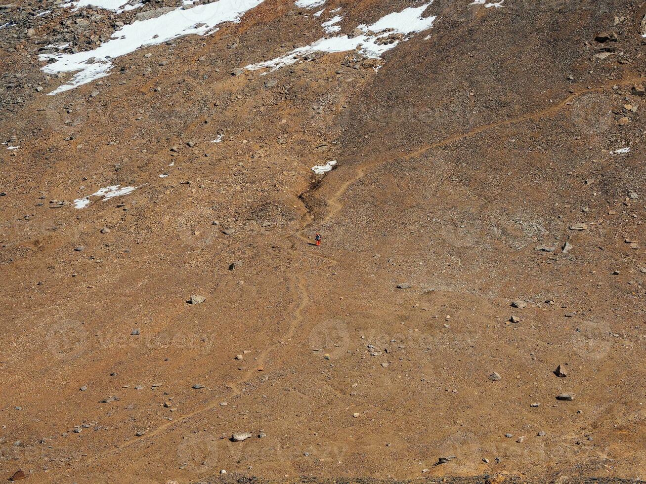 solo trekking en el montañas. hombre con un grande mochila es alpinismo fuertemente en un montaña camino. aventuras solo de viaje estilo de vida concepto, activo fin de semana vacaciones en el salvaje naturaleza. foto