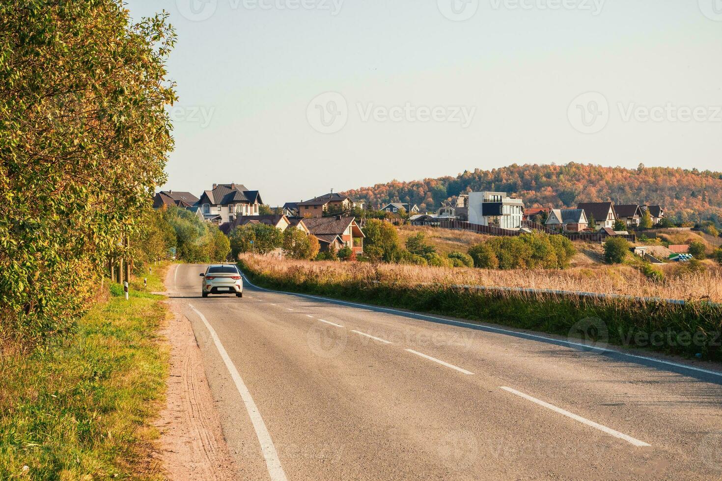 Drive along the autumn highway of the country road among the beautiful autumn hills with cottages. A sharp turn on the road photo