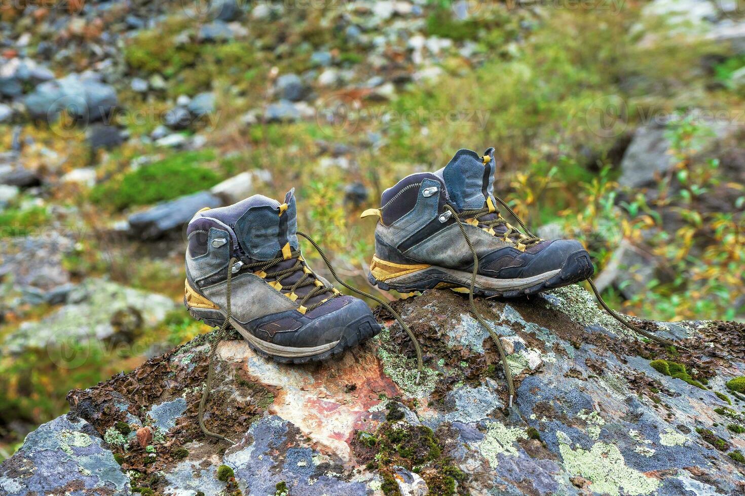 Hiking boots on drying. Wet hiking boots dry on a stone against the background of snow-covered high mountains. The difficulties of hiking, drying clothes in nature. photo