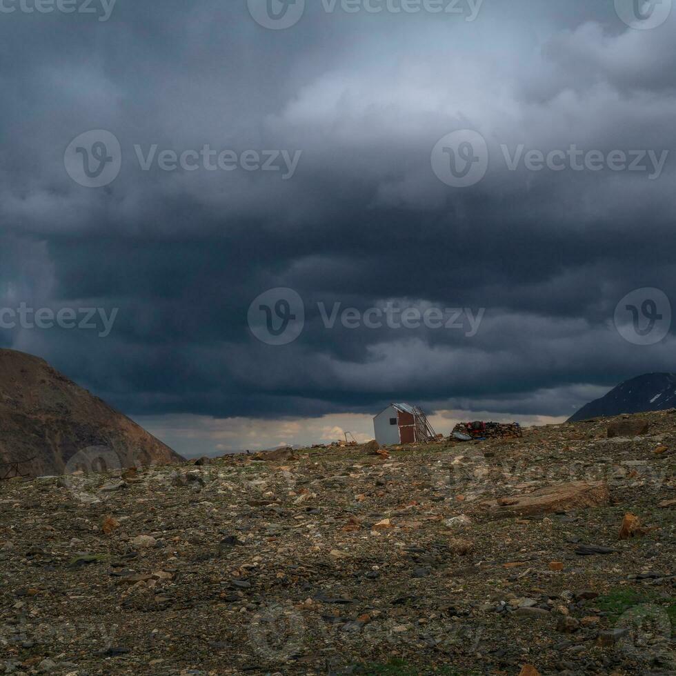 Old climbing house in the mountains under a stormy sky. Empty mountaineering camp. Authentic mountain dramatic landscape in the Altai Mountains. photo