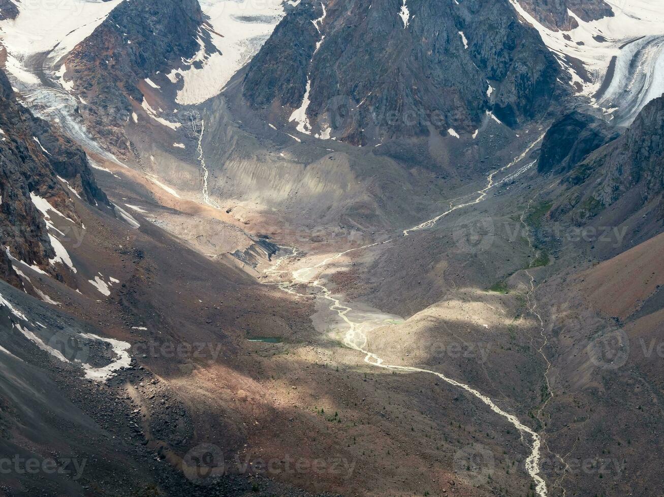 Chiaroscuro, sunlight at the bottom of the gorge. Dramatic golden light and shadow on the rock. High-altitude gorge with glacier narrow river. Aerial view. photo