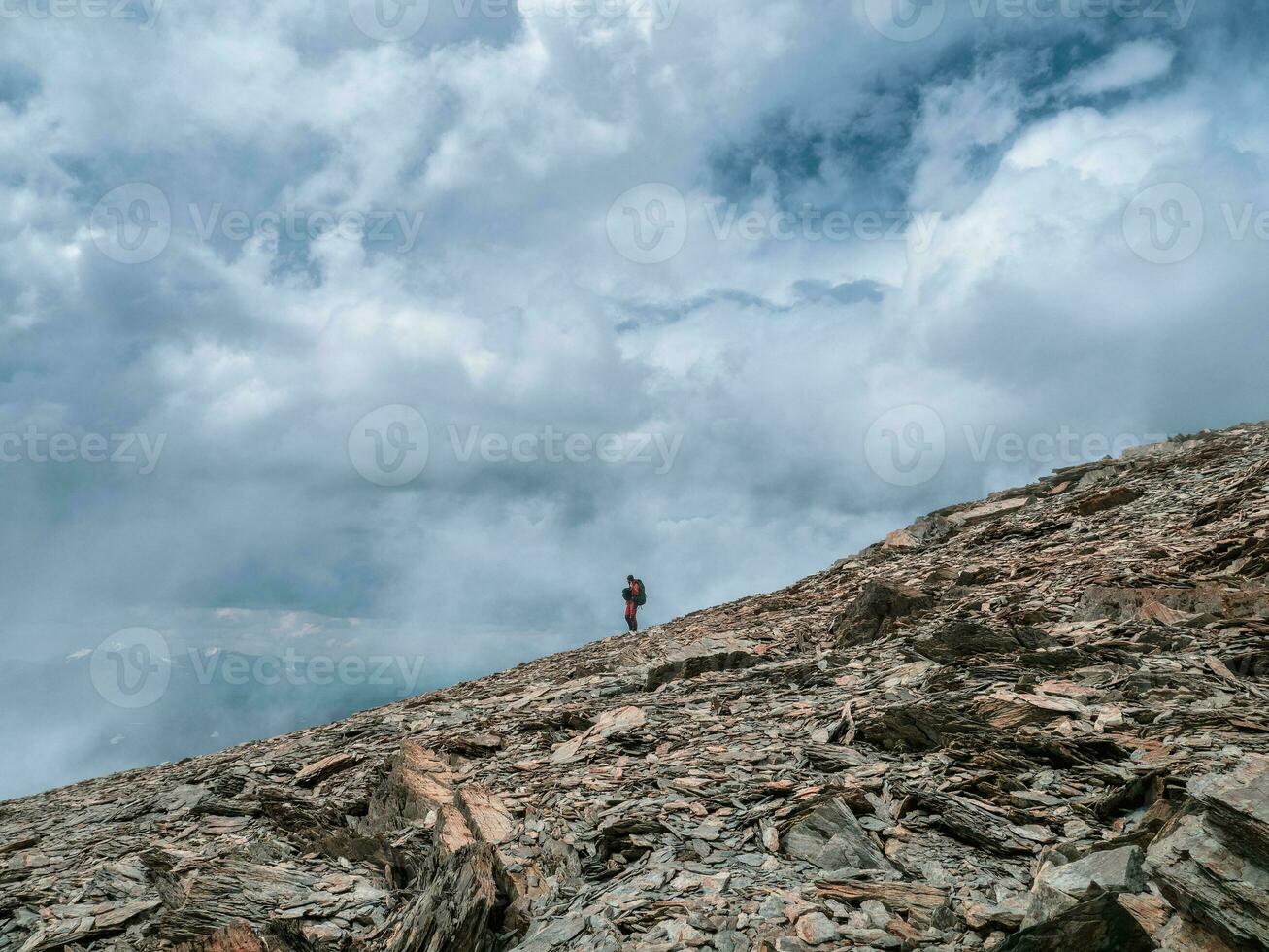 Solo hiking in the mountains. A man climbs a mountain slope.  Adventure solo traveling lifestyle concept, active weekend vacations on the wild nature. photo