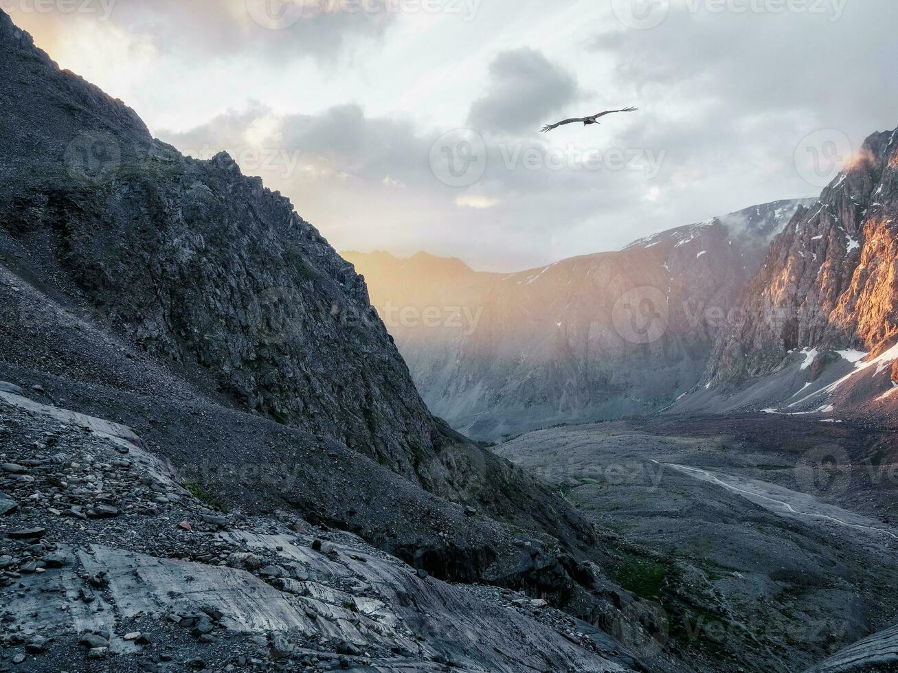 Mountain valley at sunrise. Awesome mountain valley view from cliff at very high altitude in sunrise.  Beautiful mountain scenery on abyss edge with sharp stones. photo