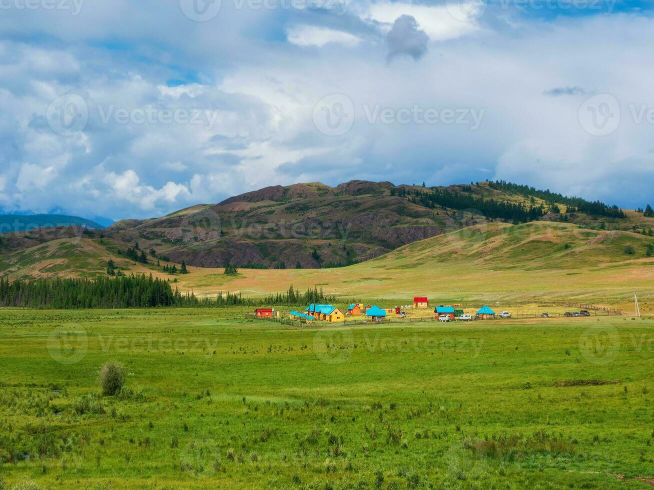 Collective camping to the distance, tourist complex, wooden guest houses against the background of green hills. Farmstead in the steppe. Countryside in highlands. photo