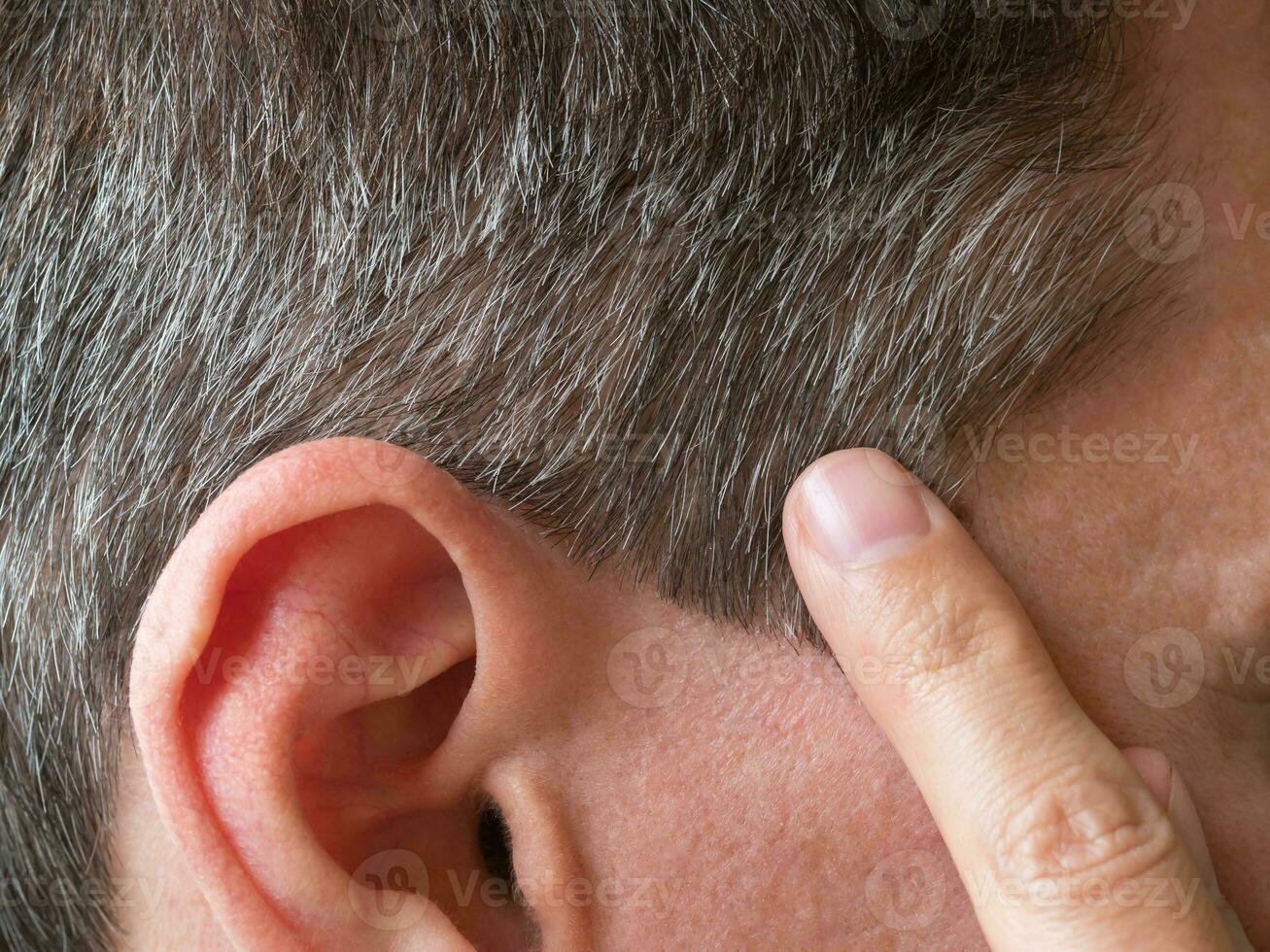 A finger pointing to the gray hair on his head. photo